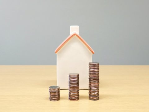 Maqueta de casa junto a monedas que representan el crédito hipotecario